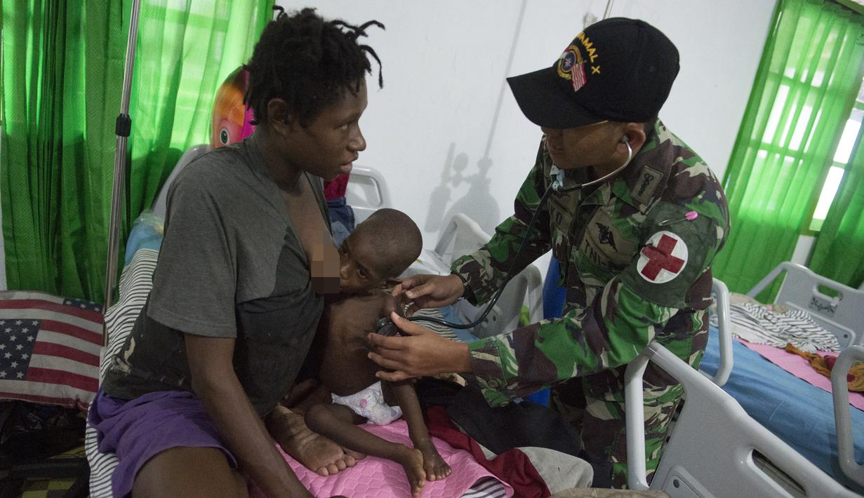 Tim medis dari satuan tugas militer Indonesia memeriksa seorang anak yang sedang menyusu pada ibunya di rumah sakit setempat di Agats, Asmat, provinsi Papua Barat (26/1). (AFP/Bay Ismoyo)