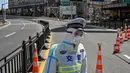 Seorang petugas transit mengenakan pakaian pelindung mengontrol akses ke jembatan ke arah distrik Pudong dalam penguncian sebagai tindakan pencegahan virus corona Covid-19  di Shanghai (29/3/2022). (AFP/Hector Retamal)