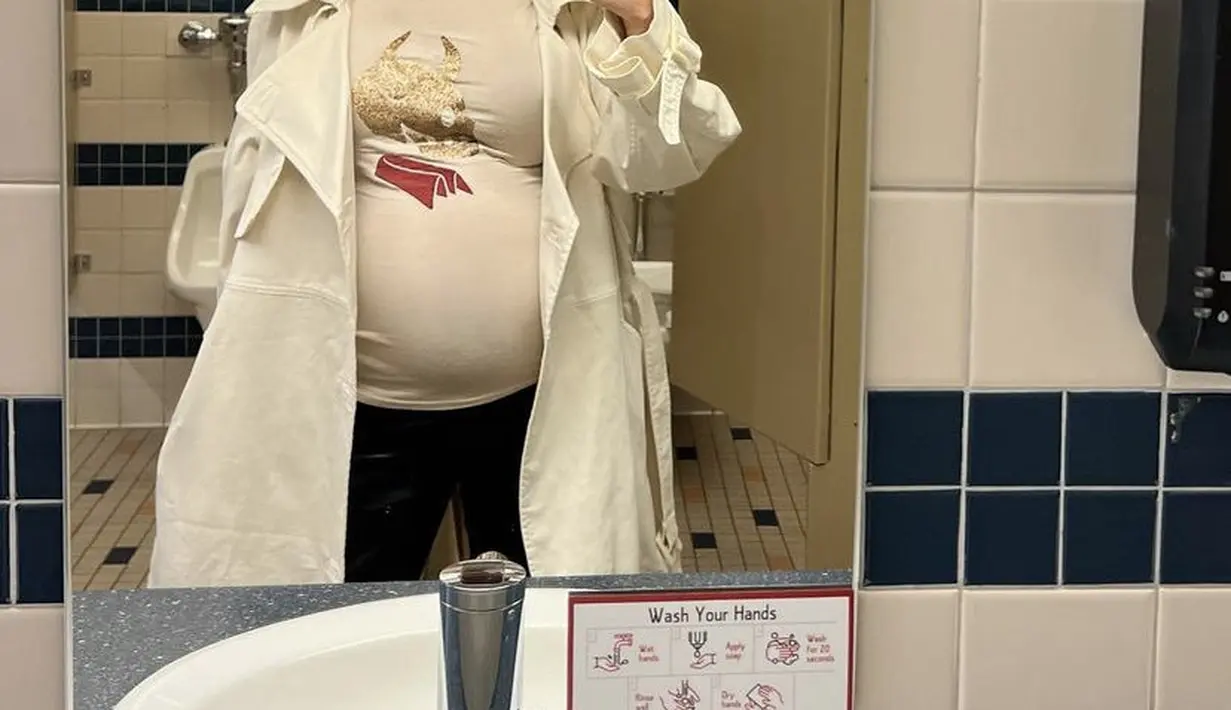 Kakak Kendall Jenner ini juga tampil tertutup dengan tshirt dan coat putih dipadukan celana hitamnya. Memerlihatkan baby bumpnya.  @kourtneykardash