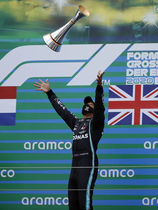 Pembalap Mercedes Lewis Hamilton melempar trofi ke udara saat merayakan kemenangan F1 GP Eifel di Nuerburgring, Nuerburg, Jerman, Minggu (11/10/2020). Hamilton dengan 91 kemenangannya menyamai legenda F1 Michael Schumacher. (Ronald Wittek, Pool via AP)