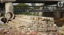 Tiang pancang dan saluran gorong-gorong menghiasi bantaran Sungai Ciliwung di kawasan Rawajati, Jakarta, Rabu (30/10/2019). Tiang-tiang pancang itu merupakan sisa proyek normalisasi Sungai Ciliwung dan telah berada di bantaran tersebut selama beberapa tahun terakhir. (Liputan6.com/Immanuel Antonius)