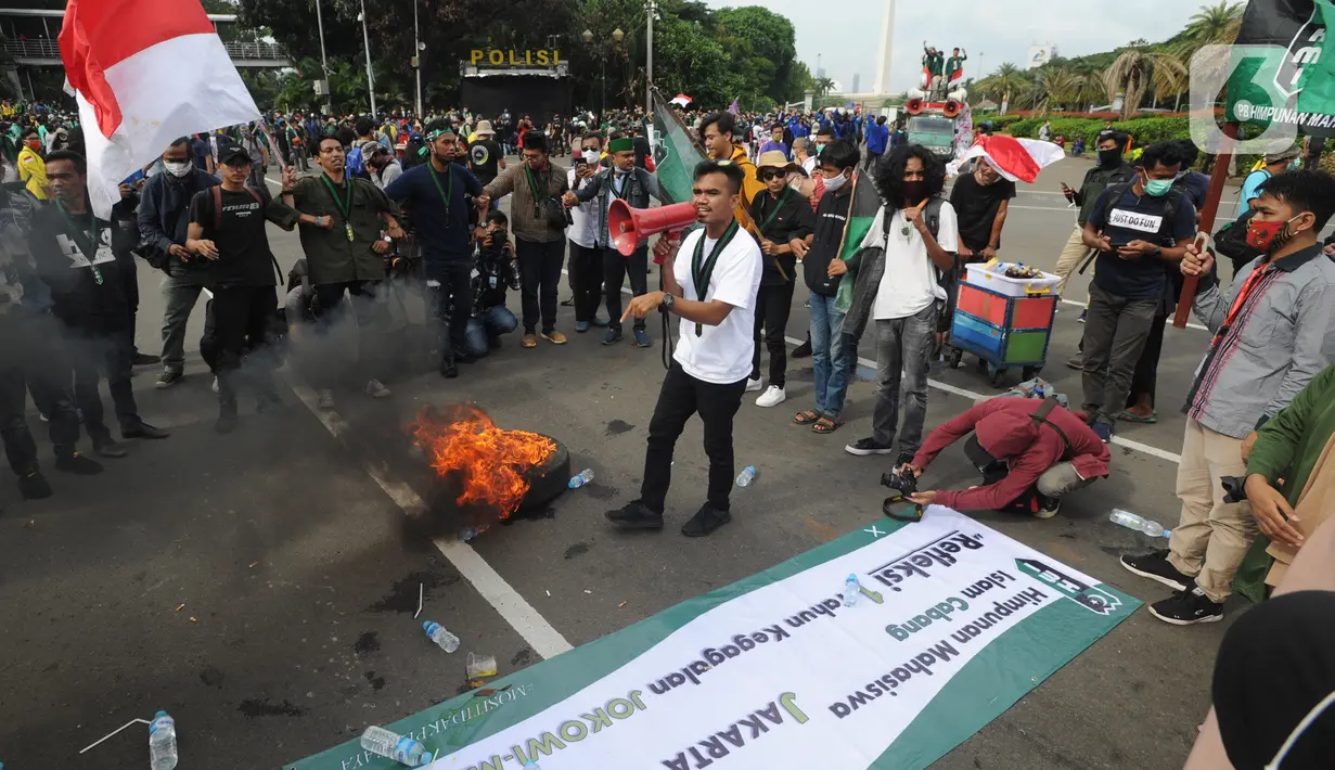 Massa Himpunan Mahasiswa melakukan aksi pembakaran ban saat aksi menolak omnibus law sekaligus refleksi satu tahun Pemerintahan Jokowi-Ma'ruf di kawasan Patung Kuda, Jakarta, Selasa (20/20/2020). Aksi ribuan pengunjuk rasa dari berbagai elemn berjalan aman. (merdeka.com/ Arie Basuki)