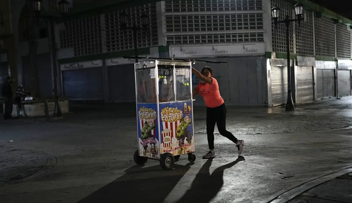 Seorang pedagang mendorong gerobak popcornnya di pusat Kota Caracas, Venezuela, 5 Februari 2022. (AP Photo/Ariana Cubillos)