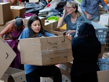 Seorang relawan membawa sekotak susu formula bayi yang diberikan untuk korban badai Harvey di pusat penggalangan dana di Dallas Utara, Selasa (29/8). Sebuah organisasi nirlaba Amerika Charity Navigator mengatur penggalangan dana ini. (Tony Gutierrez/AP)