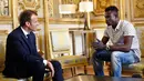 Presiden Prancis Emmanuel Macron (kiri) berbincang dengan Mamoudou Gassama di Istana Elysee, Paris, Prancis, Senin (29/5). Imigran asal Mali tersebut memperoleh penghargaan setelah menyelamatkan seorang balita di Paris. (AP Photo/Thibault Camus, Pool)