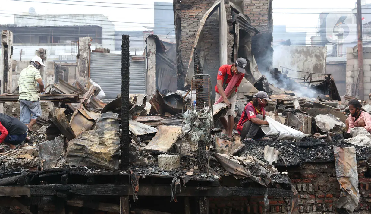 Warga memunguti sisa barang di pemukiman yang hangus terbakar di kawasan Duri Utara, Tambora, Jakarta, Rabu (12/8/2020). Kebakaran besar terjadi di kawasan padat penduduk di Jalan Duri Utara, Tambora, Selasa (11/8) malam, diduga akibat korsleting listrik. (Liputan6.com/Helmi Fithriansyah)