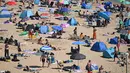 Para pengunjung berjemur menikmati sinar matahari di Pantai Bournemouth, Selatan Inggris pada Selasa 26 Mei 2026, saat kondisi gelombang panas menyebar ke sebagian wilayah tenggara Inggris dan London. (JUSTIN TALLIS/AFP)