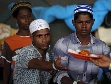 Para pengungsi etnis Rohingya saat menerima makanan di tempat penampungan, Kuala Langsa, Aceh (25/5/2015). Pemerinta RI mengalokasikan bantuan sebesar Rp 2,3 Miliar untuk pengungsi Rohingya yang berada di Aceh. (Reuters/Darren Whiteside)