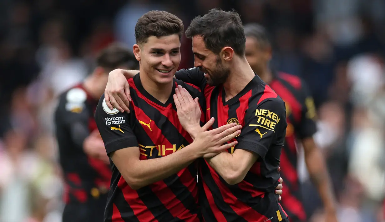 Pemain Manchester City, Julian Alvarez (kiri), mendapatkan selamat dari Bernando Silva setelah mencetak gol ke gawang Fulham dalam pertandingan pekan ke-34 Premier League 2022/2023 yang berlangsung di Craven Cottage, Minggu (30/4/2023). (AFP/Adrian Dennis)