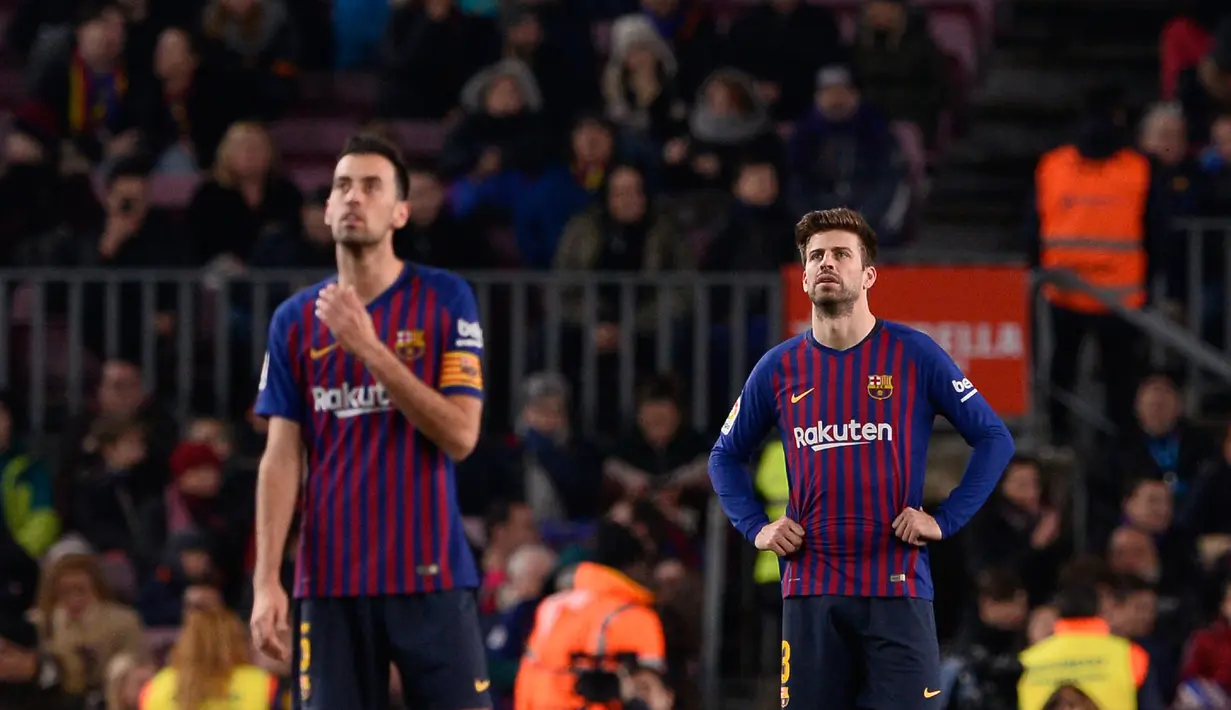 Pemain Barcelona, Sergio Busquets (kiri) dan Gerard Pique bereaksi selama pertandingan pekan ke-20 La Liga Spanyol melawan Leganes di Camp Nou, Senin (21/1). Barcelona kian kokoh di puncak klasemen usai menang 3-1 atas Leganes. (Josep LAGO / AFP)