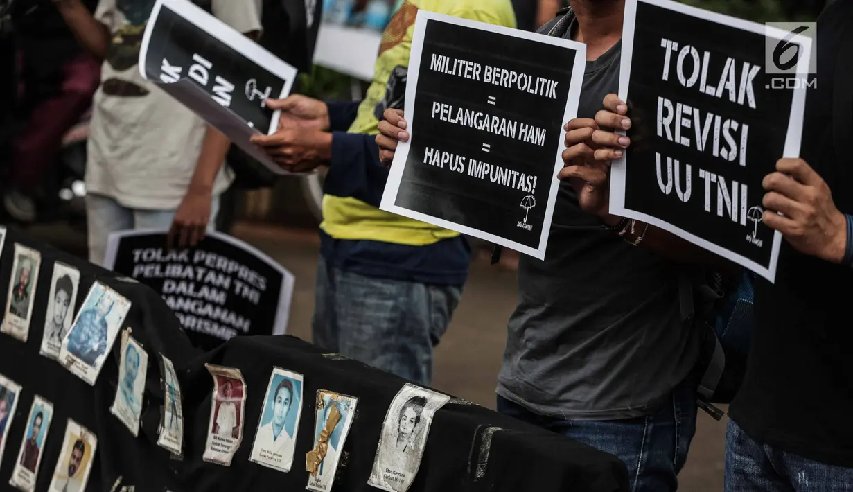 Aktivis Jaringan Solidaritas Korban untuk Keadilan (JSKK) membawa foto para korban masalah HAM masa lalu saat menggelar aksi Kamisan ke-575 di depan Istana Merdeka, Jakarta, Kamis (21/2). (Liputan6.com/FaizalFanani)