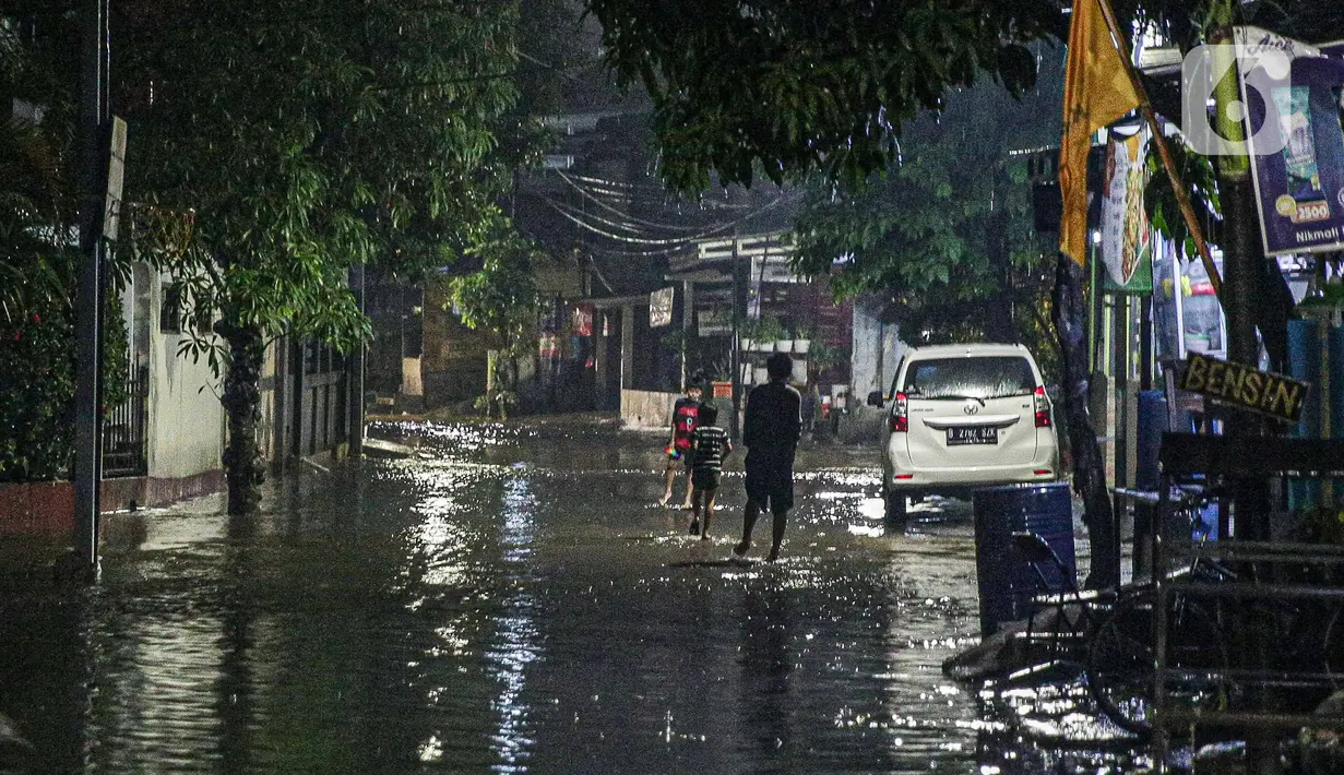 Warga melintas di genangan banjir di kawasan Mampang Prapatan, Jakarta, Sabtu (13/11/2021). Intensitas hujan yang tinggi sejak sore di Jakarta membuat kawasan permukiman di Mampang Prapatan tergenang banjir dengan tinggi sebetis orang dewasa. (Liputan6.com/Faizal Fanani)