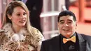 Legenda sepak bola Argentina Diego Maradona ditemani kekasihnya, Rocio Oliva saat menghadiri undian Piala Dunia 2018 di Moskow, Rusia (1/12). Rocio Oliva yang mengenakan jaket kulit harimau setia mendampingi Maradona. (AFP Photo/Kirill Kudryavtsev)