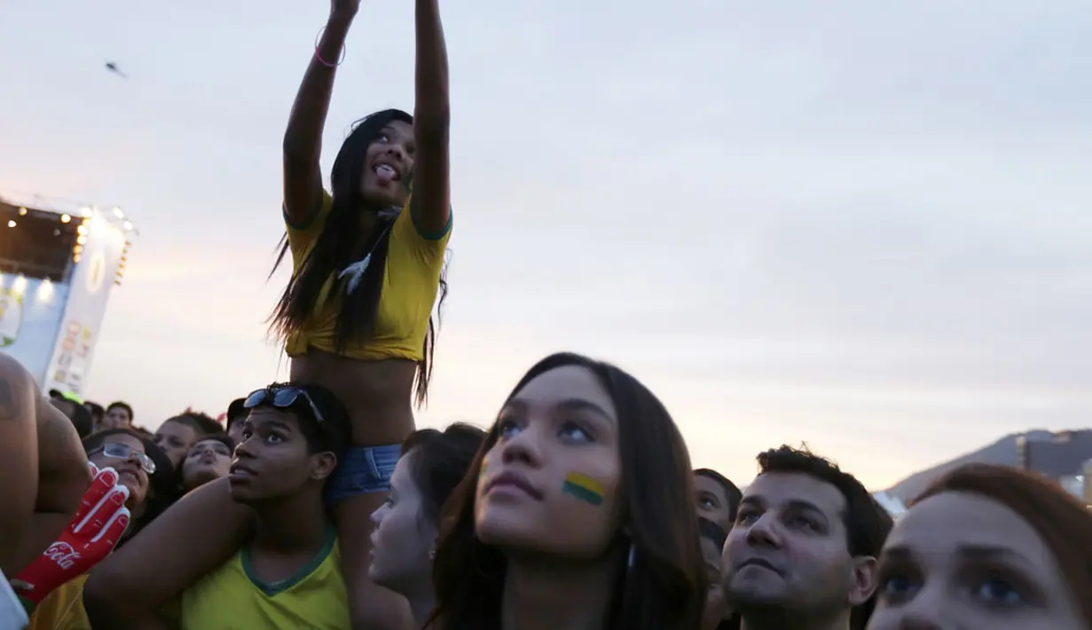 Di pantai Copacabana, Rio de Janeiro, (23/6/2014), salah satu suporter menyempatkan ber"selfie" ria sambil menyaksikan laga Kamerun vs Brasil. (REUTERS/Pilar Olivares)