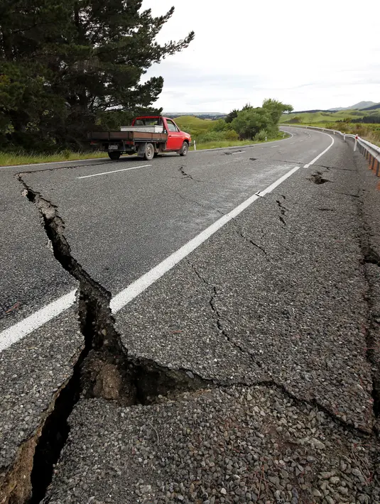 Sebuah truk melintasi jalan retak di dekat Kota Ward, selatan Blenheim, di bagian selatan Pulau Selandia Baru, Senin (14/11). Gempa 7,8 SR yang mengguncang Selandia Baru mengakibatkan jalan tersebut retak. (REUTERS/Anthony Phelps)