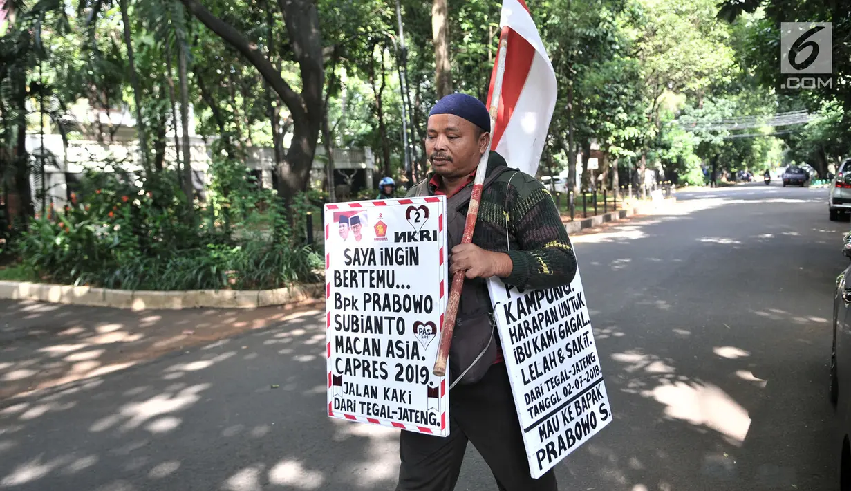 Rahman membawa poster dan bendera Merah Putih saat berjalan kaki menuju kediaman Prabowo di Kertanegara, Jakarta, Kamis (20/12). (Merdeka.com/Iqbal S. Nugroho)