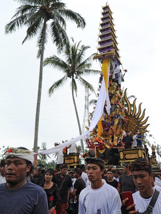 Ribuan warga mengiringi arak-arakan Bade atau menara bertingkat sembilan yang berisi jenazah anggota keluarga dari pahlawan nasional I Gusti Ngurah Rai dalam prosesi upacara Ngaben di Desa Carangsari, Badung, Bali, Senin (29/4/2019). (SONNY TUMBELAKA/AFP)