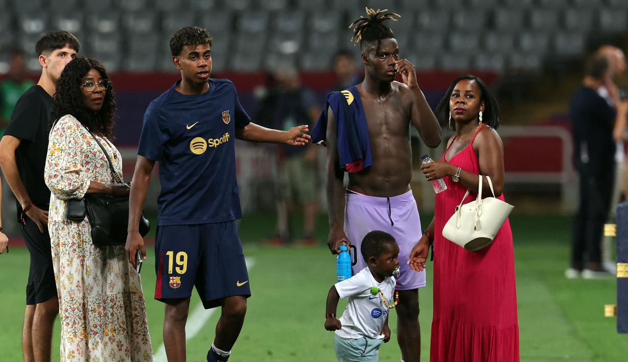 Pemain Barcelona, Lamine Yamal (tengah kiri) bersama keluarganya berbincang dengan pemain Atheltic Club Bilbao, Nico Williams setelah laga lanjutan Liga Spanyol 2024/2025 melawan Athletic Club Bilbao di Estadi Olimpic Lluis Companys, Barcelona, Sabtu (25/08/2024) waktu setempat. (AFP/Lluis Gene)