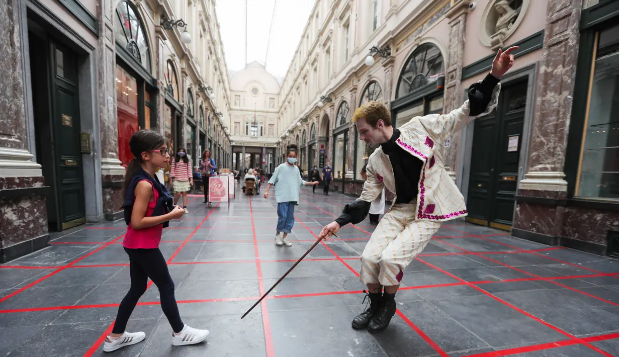 Seorang seniman memainkan permainan dalam garis persegi (grid game) dengan seorang anak gadis di Royal Gallery of Saint Hubert di Brussel, Belgia (15/7/2020). Permainan ini dirancang agar orang menghormati aturan jaga jarak sosial selama pandemi COVID-19. (Xinhua/Zheng Huansong)