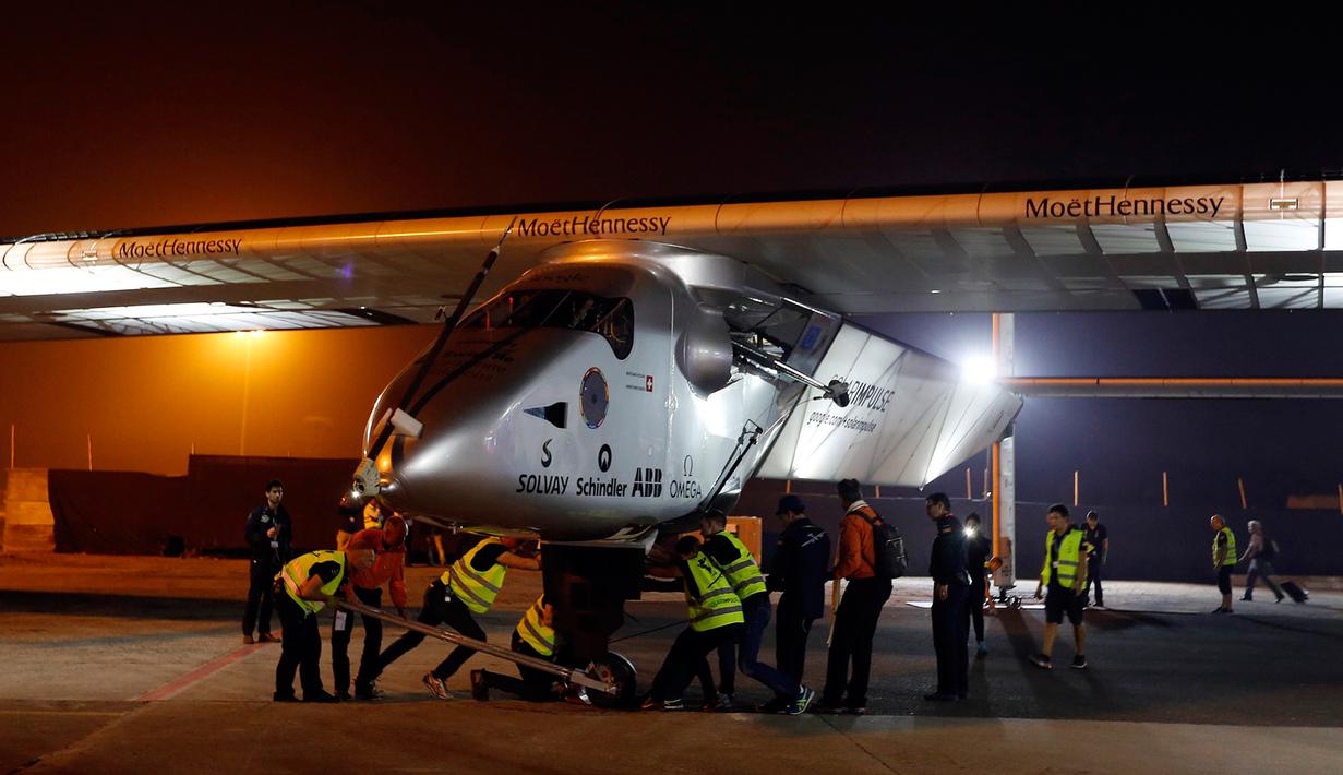 Sejumlah teknisi saat mendorong pesawat Solar Impulse 2 di bandara Ahmedabad, India, Rabu (11/3/2015). Pesawat buatan Swiss tersebut mendarat setelah menempuh perjalanan selama 15 jam.  (Reuters/Amit Dave)