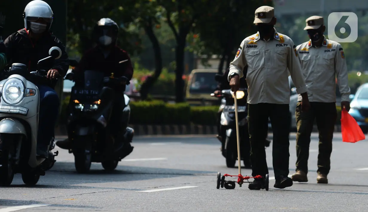 Petugas Satpol PP melakukan operasi pembersihan ranjau paku di Jalan Gatot Subroto, Jakarta, Sabtu (16/10/2021). Kegiatan penertiban ranjau paku ini untuk memberikan rasa aman dan nyaman bagi pengendara saat melintas di jalanan. (merdeka.com/Imam Buhori)