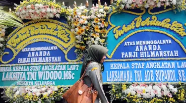 Seorang warga berjalan di deretan karangan bunga ucapan bela sungkawa atas meninggalnya putra Menteri Susi, almarhum Panji Hilmansyah di luar kediaman Menteri Kelautan dan Perikanan tersebut, Jakarta, Senin (18/1/2016). (Liputan6.com/Helmi Afandi)