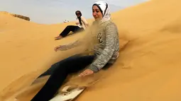 Seorang wanita mencoba berseluncur menggunakan papan sandboards di gurun pasir Wadi el-Rayan Fayoum, Mesir (18/11). Di gurun ini menyajikan banyak hiburan dan pariwisata salah satunya, berseluncur di pasir atau sandboarding. (Reuters/Mohamed Abd El Ghany)
