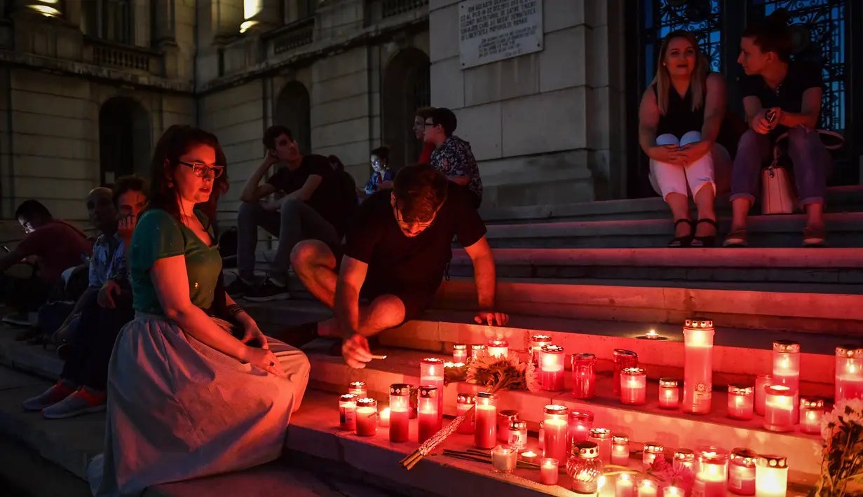 Warga menyalakan lilin untuk memperingati gadis berusia 15 tahun Alexandra yang terbunuh di depan Kementerian Dalam Negeri Rumania di Bucharest (27/7/2019). Kepala polisi Rumania telah dipecat setelah pembunuhan Alexandra yang menelepon tiga kali. (AFP Photo/Daniel Mihailescu)