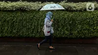 Seorang warga menggunakan payung saat hujan di kawasan Jakarta, Selasa (16/2/2021). Sebagai tahap awal vaksinasi COVID-19 tahap kedua bagi pekerja publik akan dimulai dari para pedagang Pasar Tanah Abang pada Rabu 17 Februari 2021. (Liputan6.com/Johan Tallo)