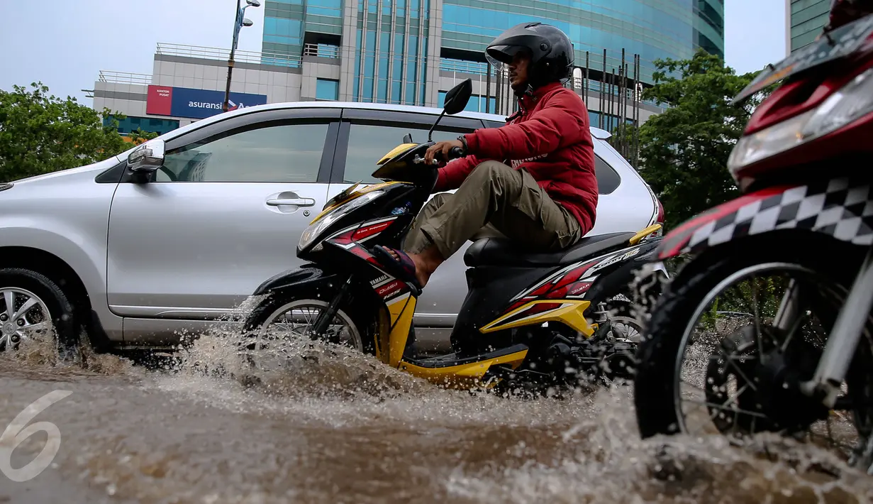 Kendaran roda dua dan empat menerjang genangan air di kawasan Kuningan, Jakarta, Selasa (24/11). Jalur lambat di Jalan HR Rasuna Said, Kuningan, tampak dihindari pengendara karena terdapat genagan air setinggi 20 cm. (Liputan6.com/Faizal Fanani)