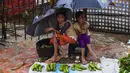 Dua anak perempuan pengungsi Rohingyah menjual pisang selama musim hujan di kamp pengungsi Kutupalong di Ukhia (12/9/2019). Kamp pengungsi Kutupalong dan Nayapara memiliki populasi sekitar 34.000 pengungsi yang terdaftar pada Juli 2017. (AFP Photo/Munir Uz Zaman)