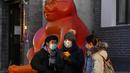 Warga yang mengenakan masker berdiri dekat patung kucing di Beijing, China, Selasa (11/1/2022. Beijing dalam siaga tinggi menjelang Olimpiade Musim Dingin saat China mengunci kota ketiga di tempat lain akibat COVID-19. (AP Photo/Ng Han Guan)