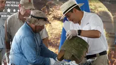 Presiden Honduras, Juan Orlando Hernandez (kanan) dan seorang arkeolog saat memamerkan benda kuno pada upacara di Catacamas, Honduras, (12/1). Benda - benda kuno ditemukan pada 2012 yang menyudut pada legenda "Kota Putih". (REUTERS / Jorge Cabrera