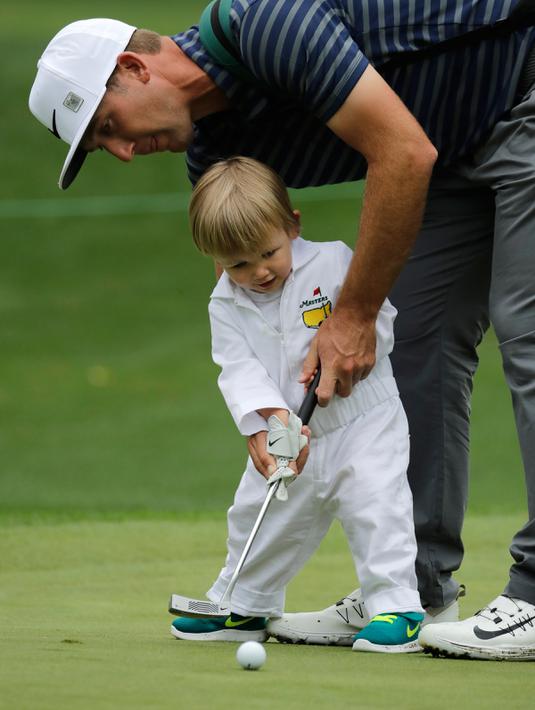 Pegolf Kevin Chappell, membantu anaknya Wyatt  Putt memasukan bola dalam acara Masters Par 3 Tournament di Augusta National Golf Club, Georgia, (5/4). (AP Photo / Charlie Riedel)