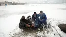 Sejumlah orang duduk di sekitar api untuk menghangatkan diri setelah hujan salju lebat di Kabul, Afghanistan, Selasa (14/1/2020). Sebanyak 24 orang dilaporkan tewas akibat cuaca buruk yang melanda Afghanistan. (AP Photo/Rahmat Gul)