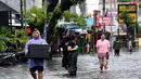 Banjir juga merendam ratusan rumah warga di sejumlah wilayah Bali. Tampak dalam foto, Para tamu hotel membawa koper mereka sambil menerobos air di jalan yang tergenang banjir akibat hujan lebat di Legian Kuta, Denpasar, Bali, pada Selasa 24 Februari 2026. (SONNY TUMBELAKA/AFP)