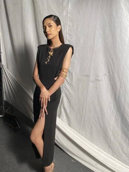 Mikha Tambayong mengenakan slit long dress hitam tanpa lengan dan detail cut outnya. Dilengkapi aksesori kalung emasnya. @mikhatambayong