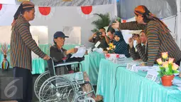 Petugas KPPS berpakaian tradisional khas Jawa dan blangkon membantu warga disabilitas saat mengikuti pencoblosan Pilkada DKI 2017 di TPS tempat Presiden Jokowi menggunakan hak suaranya, TPS 4 Gambir, Jakarta Pusat, Rabu (15/2). (Liputan6.com/Angga Yuniar)