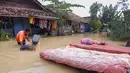 Seorang warga mengeringkan kasur dan barang-barang rumah tangga lainnya dari rumahnya yang terendam banjir di desa Sukajaya di Serang (1/3/2022).  Banjir merendam Kota Serang akibat hujan deras yang turun sejak Senin malam (28/2/2022) hingga hari ini. (AFP/Dziki Oktomauliyadi)