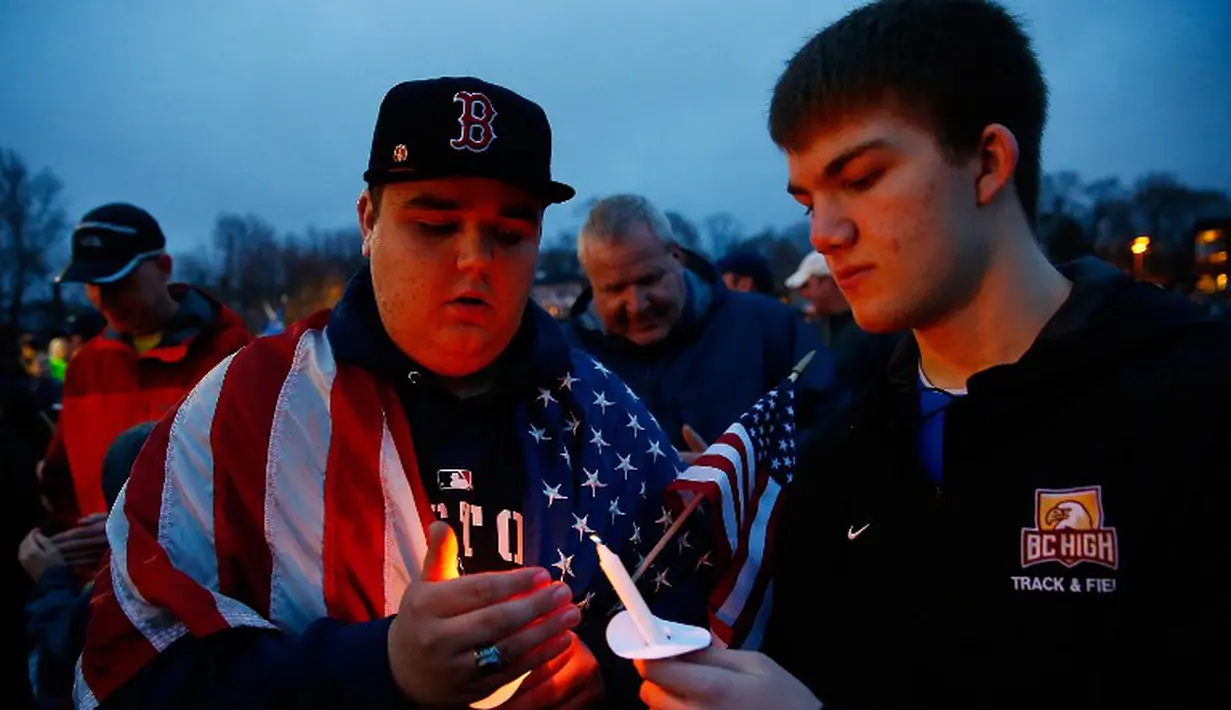 Dua warga Dorchester menyalakan lilin untuk peringatan satu tahun pemboman Boston Marathon yang menewaskan tiga orang dan melukai sekitar 264 orang lain (AFP/Jared Wickerham)