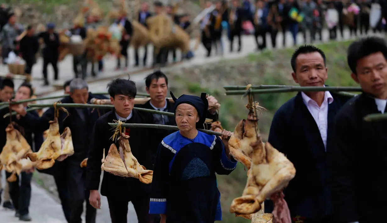 Orang-orang dari etnis minoritas Miao membawa persembahan ketika mereka menghadiri upacara pengorbanan untuk dewa gunung di Jianhe di provinsi Guizhou barat daya China (15/4). (AFP Photo/China Out)