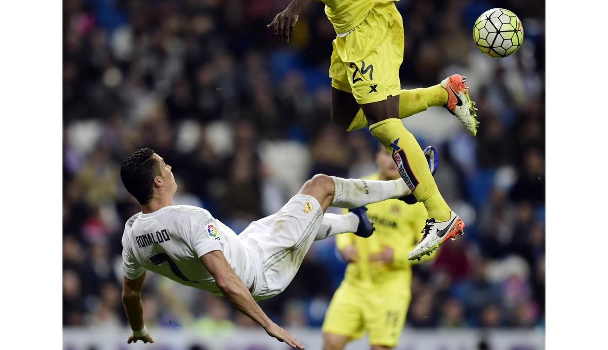 Cristiano Ronaldo melakukan tendangan salto saat dihadang pemain Villarreal, Eric Bally, pada lanjutan La Liga Spanyol di Stadion Santiago Bernabeu, Madrid, Rabu (20/4/2016) atau Kamis dini hari WIB. (AFP/Javier Soriano)