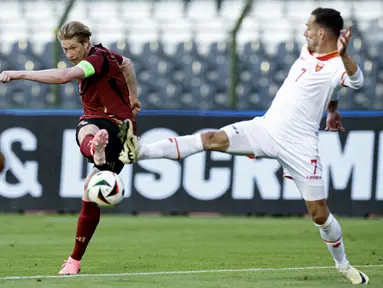 bola dengan bek Montenegro Marko Vesovic dalam duel uji coba internasional jelang Euro 2024 di Stade Roi Baudouin, Brussels, Kamis (6/6/2024). (Kenzo TRIBOUILLARD / Belga / AFP)