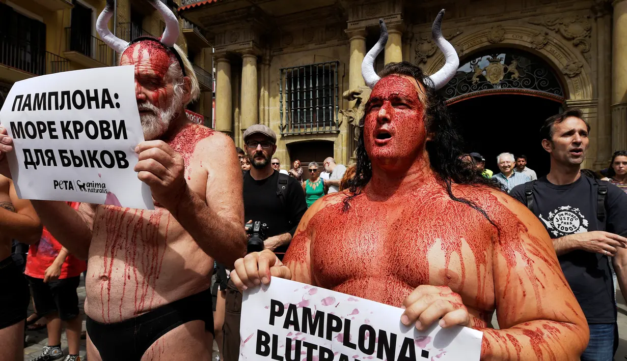 Sejumlah aktivis membasahi wajahnya dengan darah palsu saat aksi menolak festival San Fermin di Pamplona, Spanyol, (5/7).Mereka membawa poster yang bertuliskan "Pamplona: lautan darah bagi banteng." (REUTERS/Susana Vera)