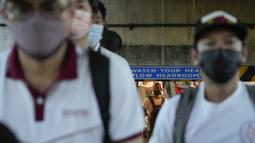 Komuter yang memakai masker berjalan menuju halte bus di Manila, Filipina, Kamis (8/9/2022). Meski penggunaan masker bukan keharusan, namun warga Filipina lanjut usia dan orang dengan gangguan kekebalan sangat dianjurkan untuk terus mengenakan masker. (AP Photo/Aaron Favila)