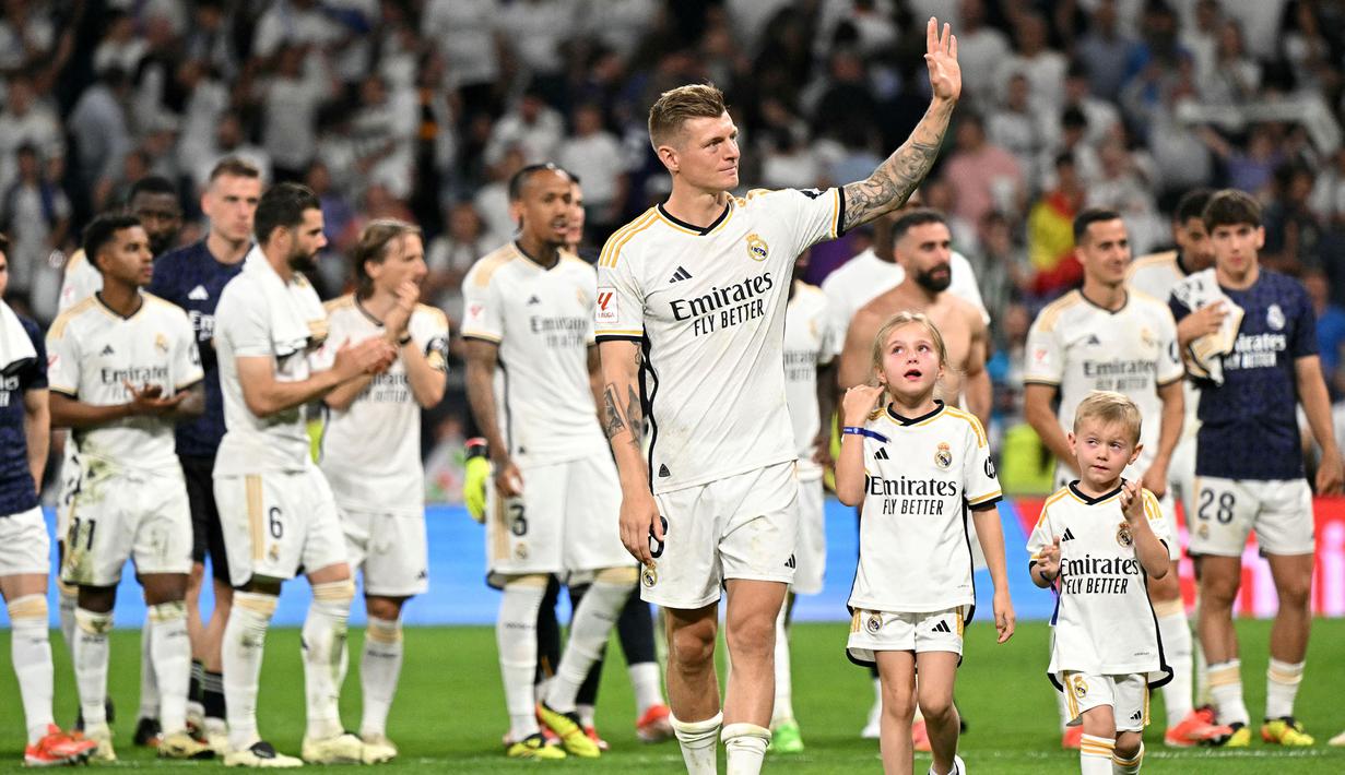 Pemain Real Madrid, Toni Kroos (tengah) bersama anak-anaknya saat melakukan perpisahan setelah laga Liga Spanyol 2023/2024 melawan Real Betis di Santiago Bernabeu, Madrid, Spanyol, Minggu (26/05/2024) dini hari WIB. Kroos memutuskan untuk pensiun dari sepak bola setelah Euro 2024 nanti. (AFP/Javier Soriano)