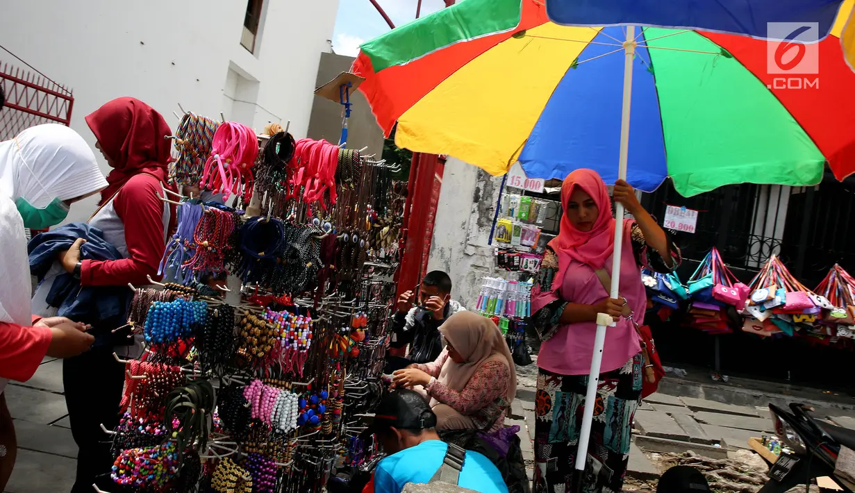 Pedagang gelang tangan berjualan di kawasan Kota Tua, Jakarta Selasa (2/1). Suasana libur tahun baru dimanfaatkan pedagang untuk menggelar dagangannya di kawasan tersebut. (Liputan6.com/Johan Tallo)