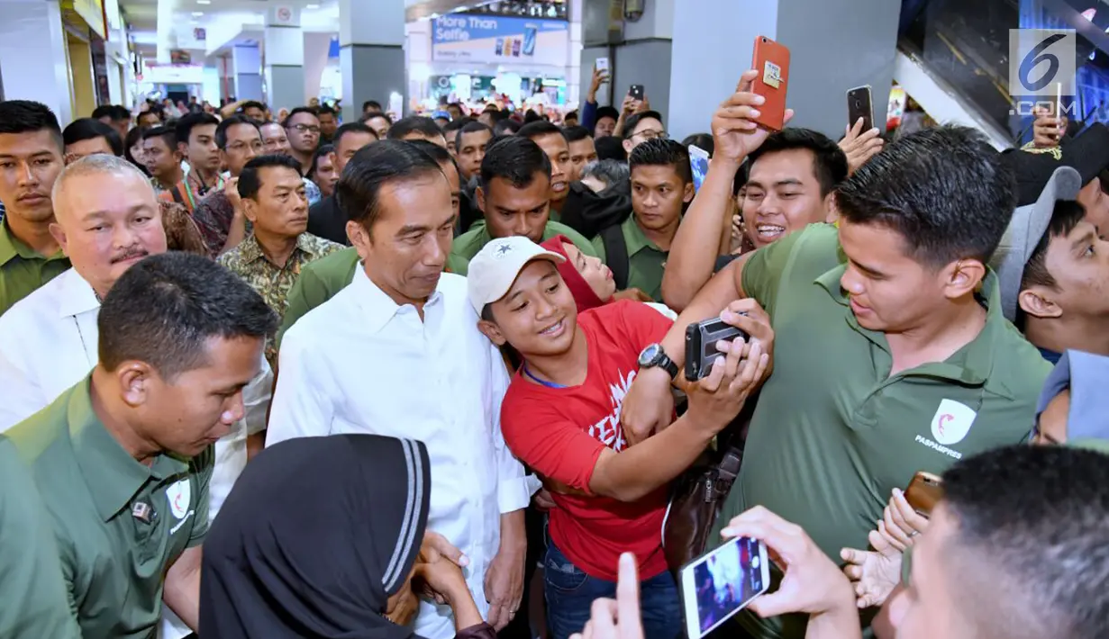 Seorang remaja berswafoto dengan Presiden Joko Widodo atau Jokowi saat menyambangi Palembang Square, Palembang (21/1). Banyak warga terkejut mengetahui kedatangan Presiden di sebuah mal Palembang tersebut. (Liputan6.com/Pool/Biro Setpres)