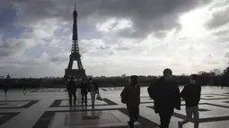 Orang-orang yang memakai masker berjalan di alun-alun Trocadero, dekat Menara Eiffel, di Paris, Kamis (19/11/2020). Prancis telah melampaui 2 juta kasus virus corona COVID-19 yang dikonfirmasi, total tertinggi keempat di dunia. (AP Photo/Michel Euler)