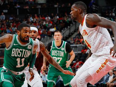 Pebasket Boston Celtics, Kyrie Irving, berusaha melewati pebasket Atlanta Hawks, Dewayne Dedmon, pada laga NBA di Philips Arena, Atlanta, Senin (6/11/2017). Hawks kalah 107-110 dari Celtics. (AFP/Kevin C Cox)